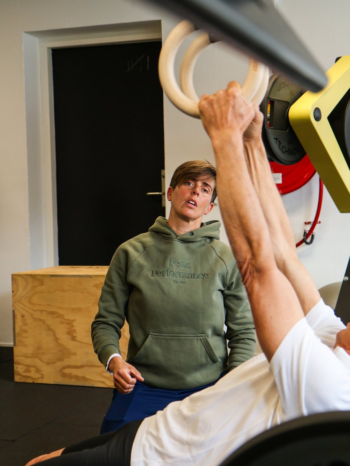 Clara Hamstra ondersteunt een client die aan de ringen hangt